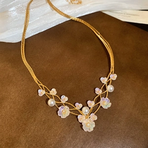 Close-up of golden layered necklace with holographic flower petals and elegant pearls
