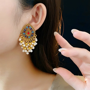 Gros plan de boucles d'oreilles vintage en or avec émail coloré et glands de perles blanches