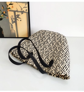 Detail of two-tone paper rope woven tote with black leather strap on a minimalist background