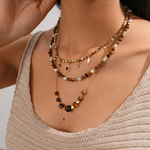 Close-up of bohemian layered gold necklace featuring sun pendant and tiger eye beads