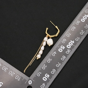 Elegant C-shaped gold-plated earrings with natural pearls and tassel chains on black background
