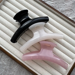 Three jelly color shark hair clips in black, white, and pink on a jewelry tray