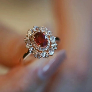 Vintage gold ring with oval red gemstone and hollow diamond setting on female hand