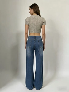 Vista posteriore di jeans blu a gamba larga a vita alta con tasche e crop top grigio