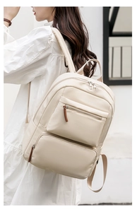 Side view of beige nylon backpack on model showing large capacity pockets and straps