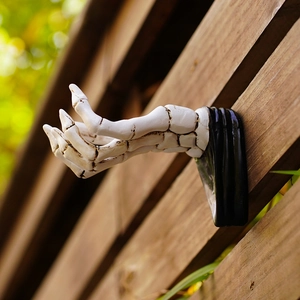 Close-up of white 3D skeleton hand wall hook with gothic resin texture and black base