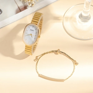 Detailed close-up of golden oval quartz watch and matching bracelet set on desk