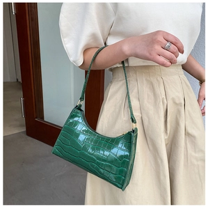 Detail of green crocodile pattern shoulder bag featuring glossy finish and gold zipper