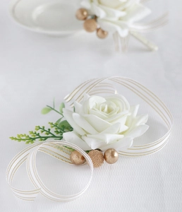 Macro detail of handmade white silk rose boutonniere with gold pearls and ribbon