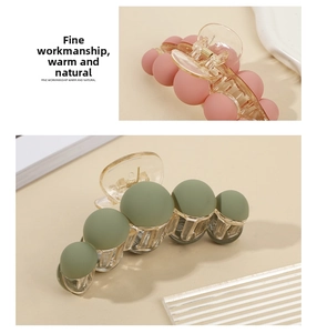 Detail view of large matte resin claw clips in pink and green with spherical beads