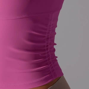 Détail d'un haut de yoga rose avec fronces latérales et texture de maille respirante