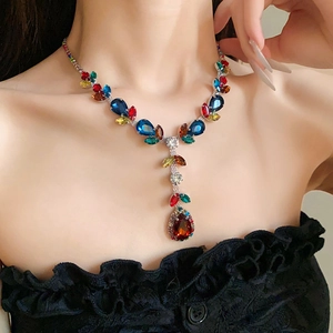 Macro detail of leaf drop necklace with colorful zircons on a model for evening wear