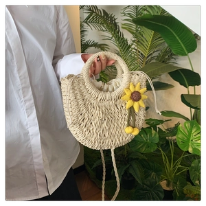 Detail einer handgewebten Strohtasche in Beige mit Sonnenblume und rundem Tragegriff