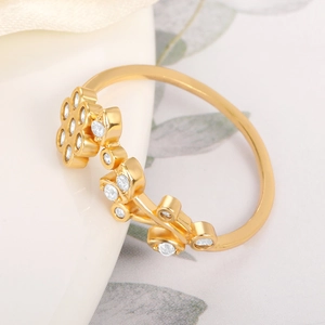Detail of gold flower ring with white gemstones and elegant vine patterns on a white background