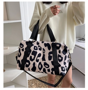 Cow print oxford travel bag with dual handles and adjustable shoulder strap shown on model