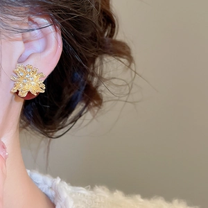 Detailed view of fireworks-inspired gold pearl earrings with sparkling zircons on a model