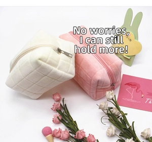 Detail view of quilted velvet pencil bags in cream and pink with silver zippers