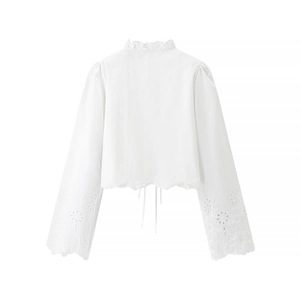 Detail of white blouse back showing delicate openwork embroidery and ruffle hem with lace-up ties