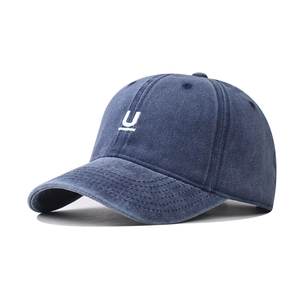 Macro shot of white U-shaped embroidery on washed navy blue vintage cotton baseball cap