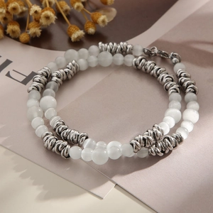 Détail de perles d'opale blanche et d'anneaux argentés sur un bracelet à deux rangs