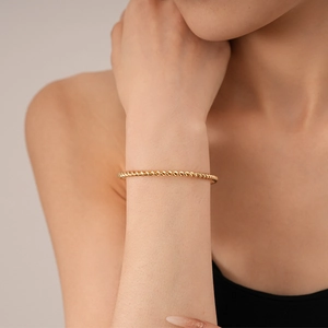 Minimalist twisted gold bangle bracelet for women with elegant metallic spiral texture