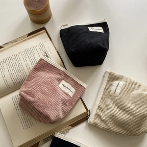 Flat lay of vintage corduroy pouches in black, pink, and beige with chic white zippers