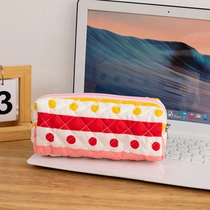 Detailed macro view of quilted cotton cosmetic bag with colorful polka dots and stripes