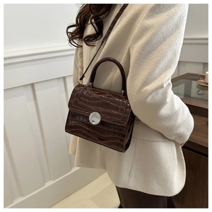 Detail of dark brown faux crocodile leather bag with silver buckle and crossbody strap