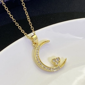 Detailed macro shot of gold moon and heart pendant necklace with micro-pave crystals