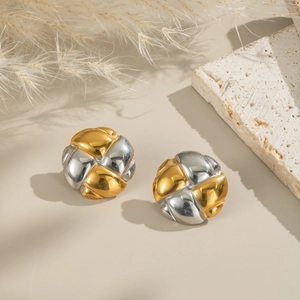 Detail of twisted knot earrings in gold and silver finish on a travertine stone