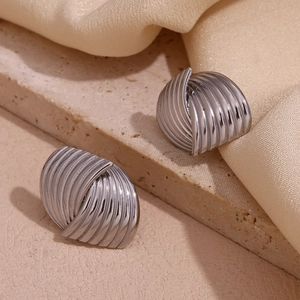 Macro detail showing silver textured fan-shaped earrings on textured stone and satin cloth