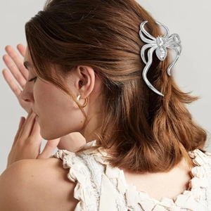 Detail of silver spider hair claw clip worn on hair showing a stylish spider design