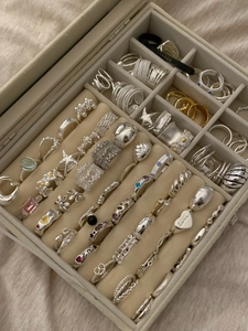 Jewelry box storage showcasing silver and gold rings with a ring sizer tool in detail