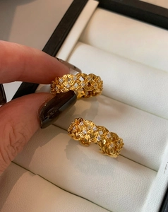 Close-up of gold plated hollow crisscross ring with zircons in a jewelry box