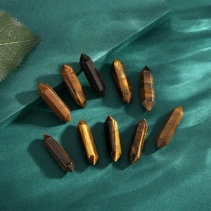 Detailed macro view of ten polished tiger eye hexagonal crystal pillars on textured green paper