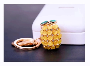 Macro detail of pineapple keychain with yellow cat eye stones and green leaves