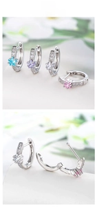 Detail view of star-shaped zircon huggie earrings in blue, purple, white, and pink