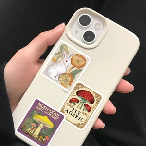 Close-up of vintage mushroom and rabbit stickers applied on a beige mobile phone case