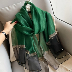 Detailed close-up of silk scarf featuring green and black panels with gold bead trim