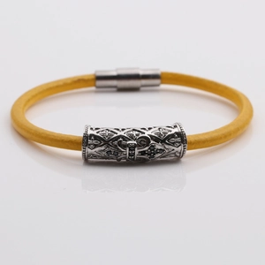 Detail of yellow braided leather bracelet with silver magnetic clasp and cross charm