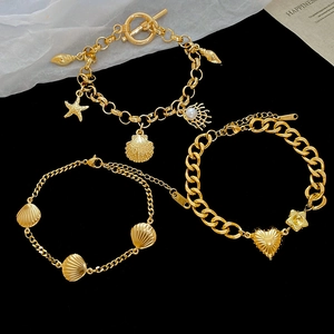 Detailed view of three gold ocean-themed bracelets with shells, starfish, and heart charms