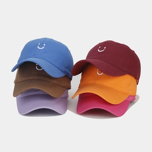 Close-up of embroidered smiley face logo on colorful structured cotton baseball caps