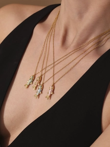 Detail of four golden stainless steel necklaces with colorful enamel fish pendants on model