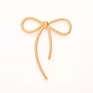 Golden bow-shaped zinc alloy accessory with elegant textured lines on white background