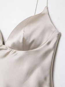 Detailed close-up of champagne gold satin fabric texture and slim shoulder straps