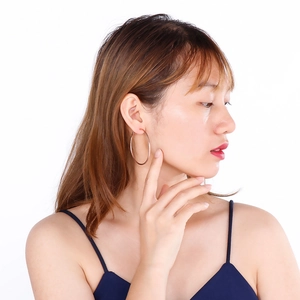 Minimalist large hoop earrings in rose gold finish shown on model with white background