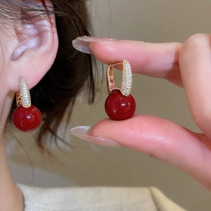 Detailed view of vintage gold earrings with zircon micro-pave and red resin sphere pendant