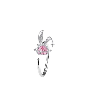 Close-up of silver rabbit ear ring with pink heart gem and star pendant detail