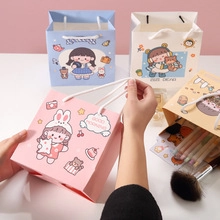 Handheld view of cartoon gift bags in pink, blue, white, and yellow for party favors