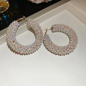 Elegant gold hoop earrings with white pearls and iridescent crystals on jewelry tray